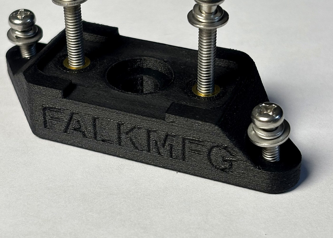 Black FDM printed fixture with metal fasteners and a central opening