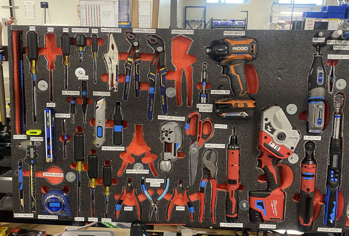 Upright foam board with labeled cutouts for drivers, pliers, cutters, and powered tools