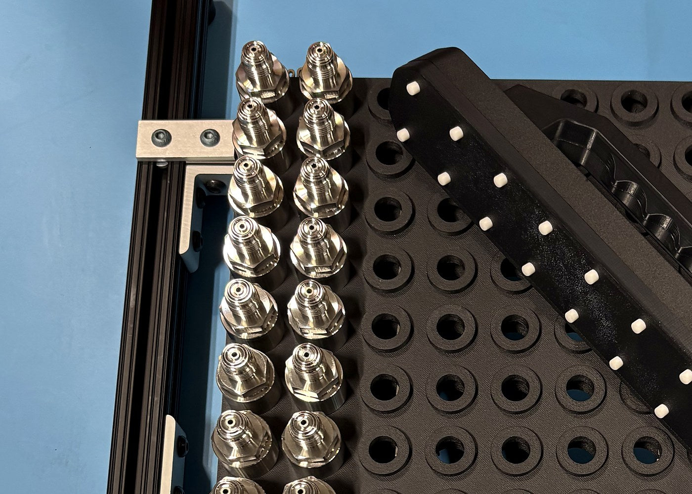 Black part-nesting fixture holding metal components on an aluminum frame