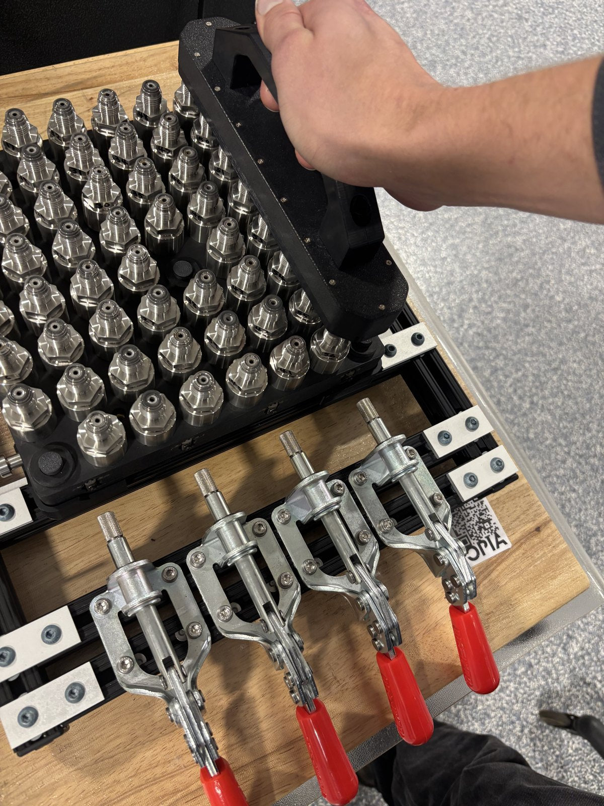 Metal components seated in the black fixture beside the toggle clamps