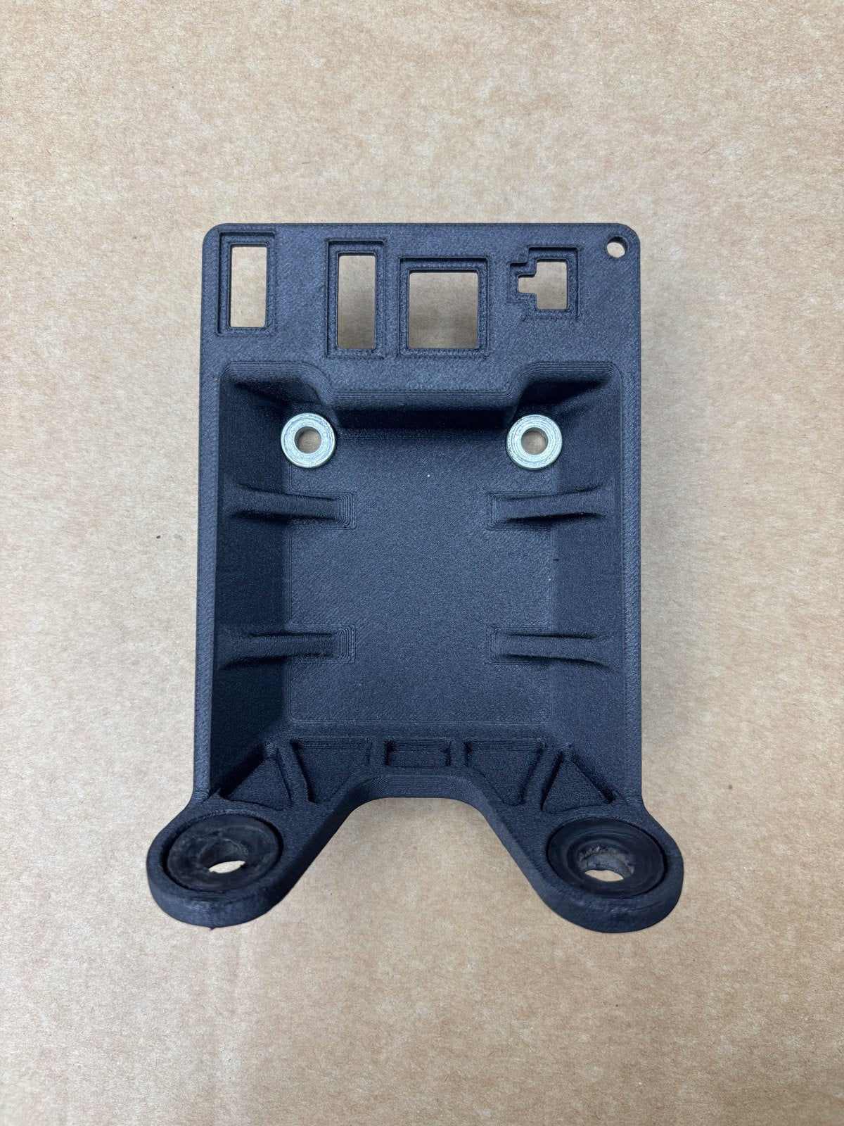 Reverse side of the black display bracket showing two inserts and four openings