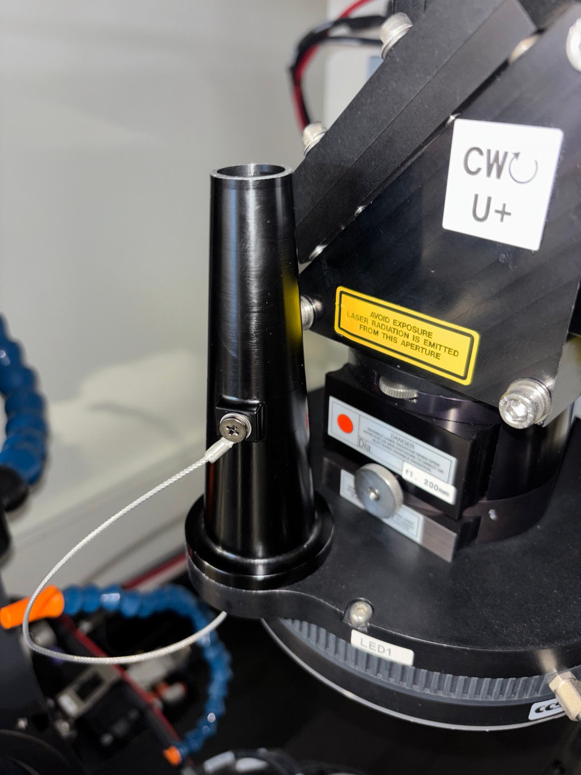 Original black nozzle mounted on the laser welding machine, with side attachment and cable visible